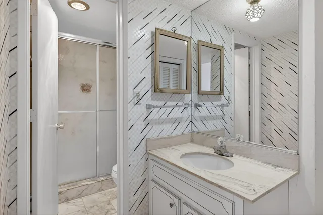 a bathroom with a granite countertop sink a mirror and shower