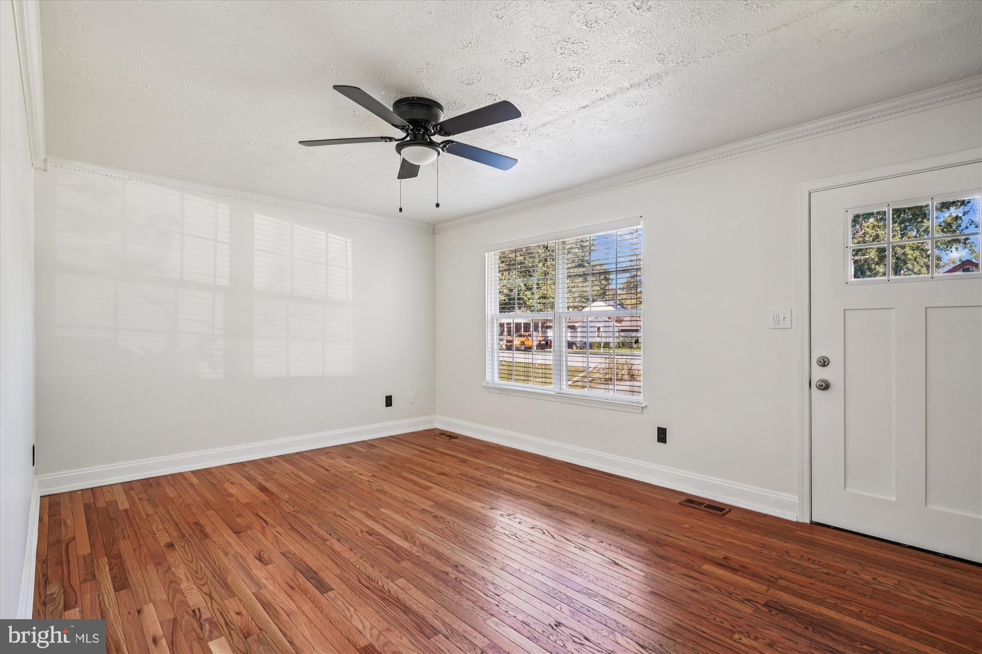 3831 8th Street North Beach, MD 20714 - Photo 4 of 37 an empty room with wooden floor fan and windows