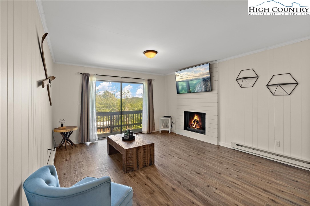 101 Mid Holiday Lane, Unit E217 Beech Mountain, NC 28604 - Photo 5 of 43 a living room with furniture a fireplace and a floor to ceiling window