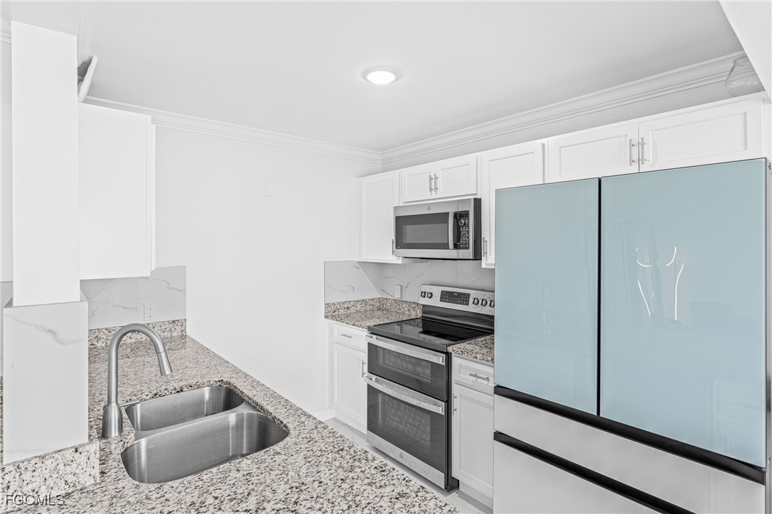 3225 East Riverside Drive, Unit 34C Fort Myers, FL 33916 - Photo 4 of 50 a kitchen with stainless steel appliances kitchen island granite countertop a refrigerator a stove a sink and white cabinets with wooden floor