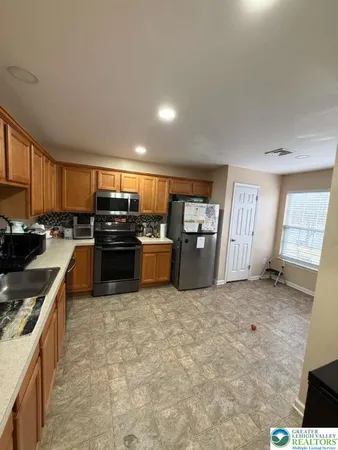 a kitchen with stainless steel appliances granite countertop a stove top oven a sink and a refrigerator