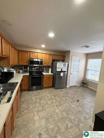 a kitchen with stainless steel appliances granite countertop a stove top oven a sink and a refrigerator
