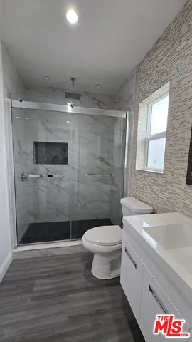 a bathroom with a toilet a sink a mirror and a shower