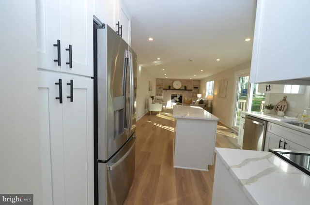 a view of a kitchen with kitchen island a counter top space a sink wooden floor and a refrigerator