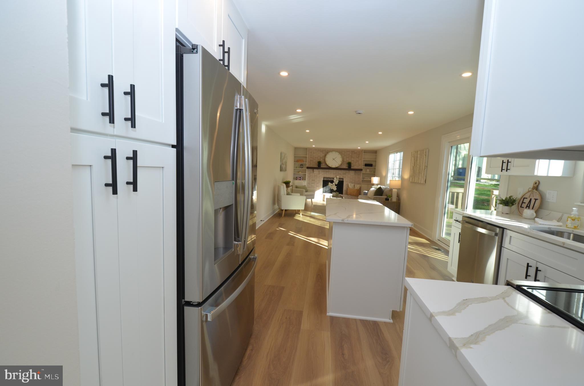 8375 Magic Leaf Road Springfield, VA 22153 - Photo 6 of 43 a view of a kitchen with kitchen island a counter top space a sink wooden floor and a refrigerator