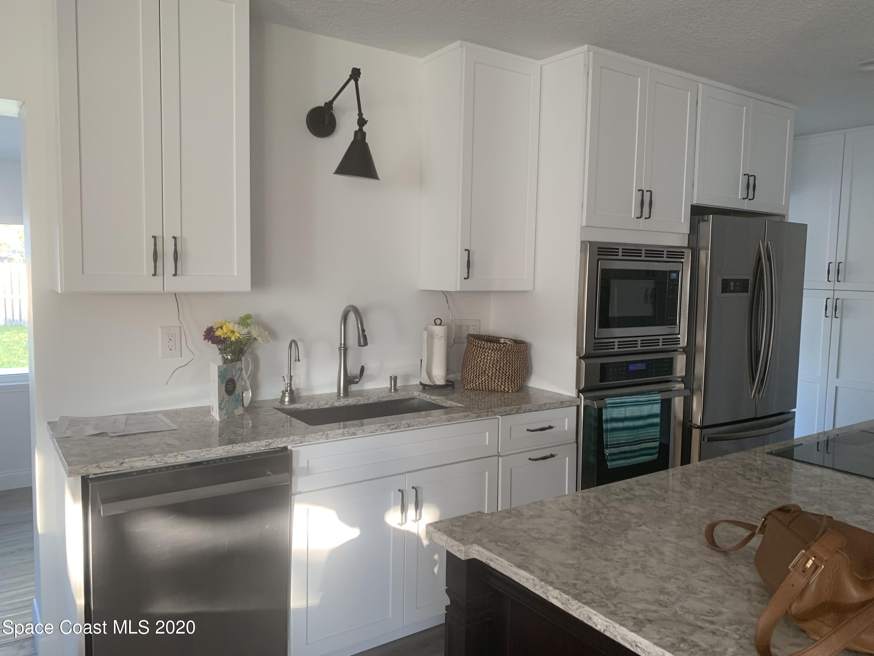120 Maple Drive Satellite Beach, FL 32937 - Photo 3 of 13 a kitchen with stainless steel appliances granite countertop a sink stove and refrigerator
