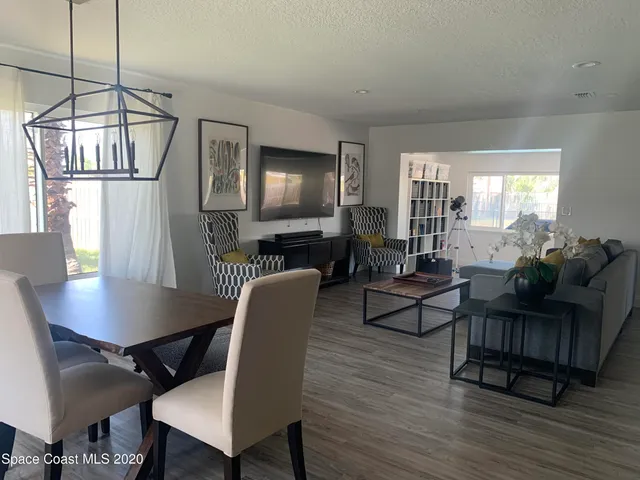 a view of a livingroom and dining room with furniture wooden floor a rug and a chandelier