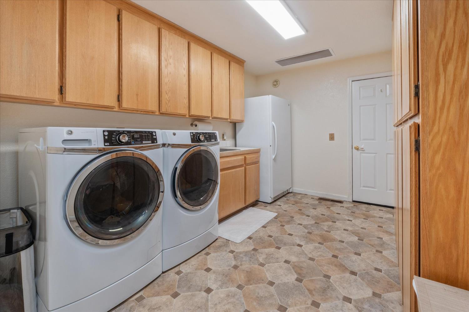 4480 Foster Court Murphys, CA 95247 - Photo 31 of 57 Huge laundry room with tons of cabinet space, utility sink, and a full-size fridge. The door leads to stairs down to the garage.