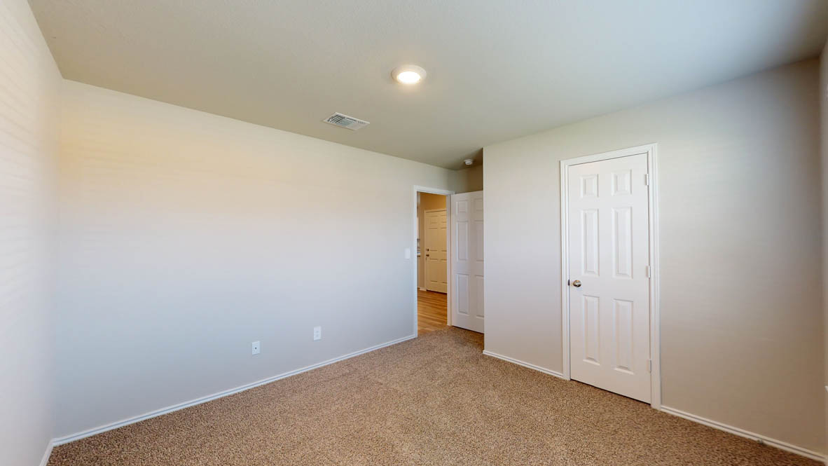 509 Hector Loop Georgetown, TX 78626 - Photo 22 of 31 A well-lit bedroom awaits, featuring comfortable carpet flooring and a crisp white door.