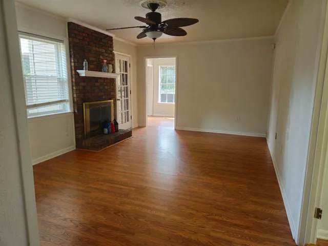 an empty room with wooden floor a fireplace and windows