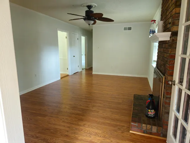 a view of empty room with wooden floor and ceiling fan