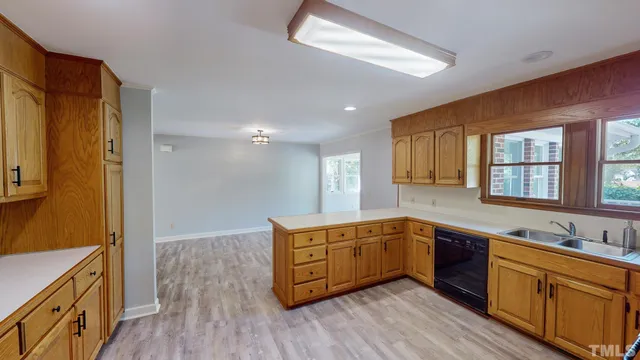 a large kitchen with stainless steel appliances granite countertop a sink and wooden cabinets