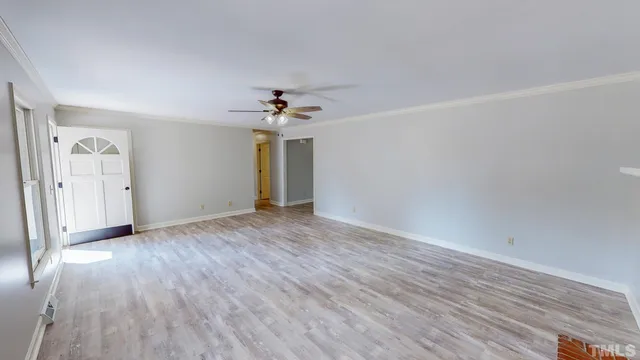 an empty room with wooden floor and chandelier fan