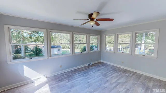 a view of an empty room with wooden floor and a window