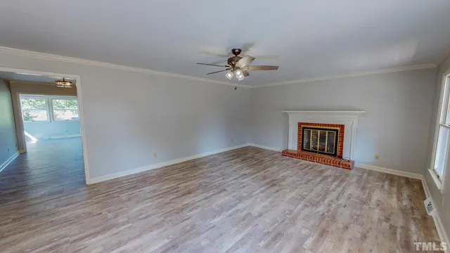 an empty room with wooden floor chandelier fan and windows
