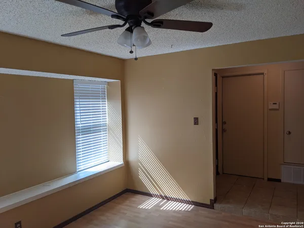 an empty room with windows and fan