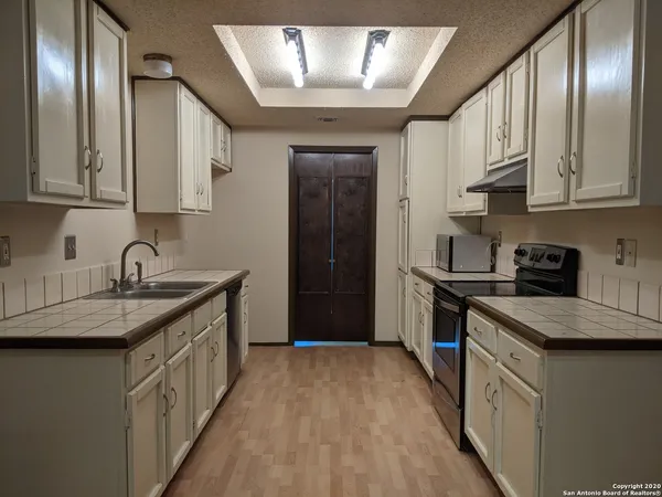 a kitchen with granite countertop stainless steel appliances a sink stove top oven and cabinets