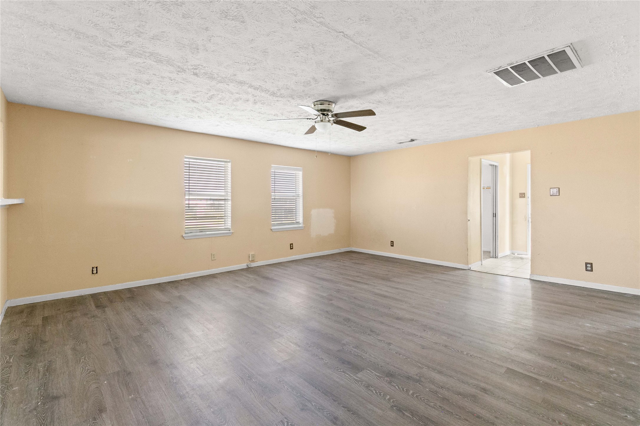 910 Monument Drive Surfside Beach, TX 77541 - Photo 10 of 29 an empty room with wooden floor ceiling fan and windows