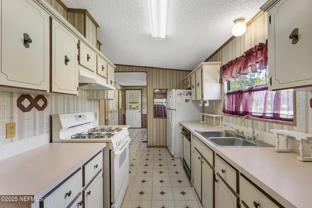 a kitchen with granite countertop appliances a sink and a refrigerator