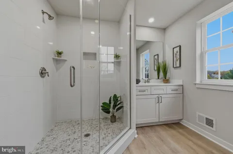 a bathroom with a granite countertop sink a mirror a vanity and a shower