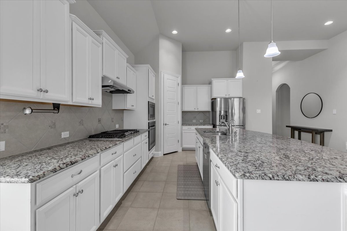 21301 Resource Road Pflugerville, TX 78660 - Photo 5 of 29 Gourmet kitchen featuring a large island with sink, stainless steel appliances, recessed lighting, white cabinetry, and granite countertops