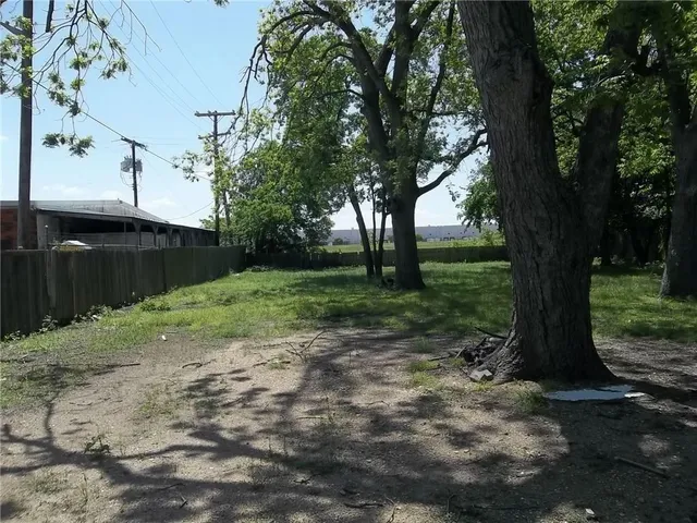 a view of a yard with wooden fence and a large tree