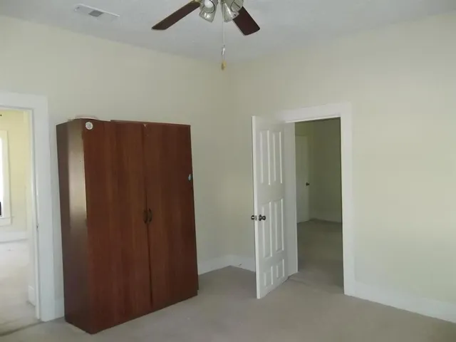 an empty room with closet and a ceiling fan
