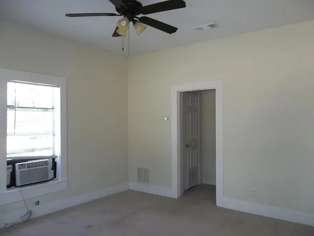 an empty room with a window and a ceiling fan