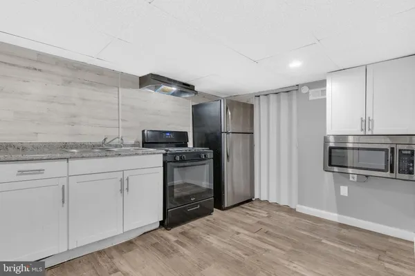 a kitchen with granite countertop a refrigerator and a stove top oven