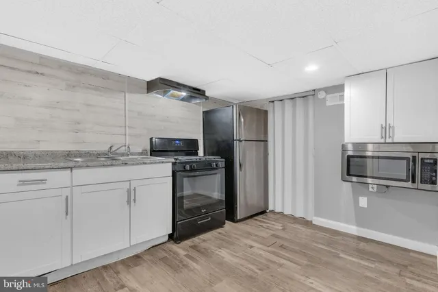 a kitchen with granite countertop a refrigerator and a stove top oven
