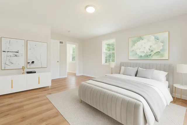 a spacious bedroom with a bed and a painting on the wall