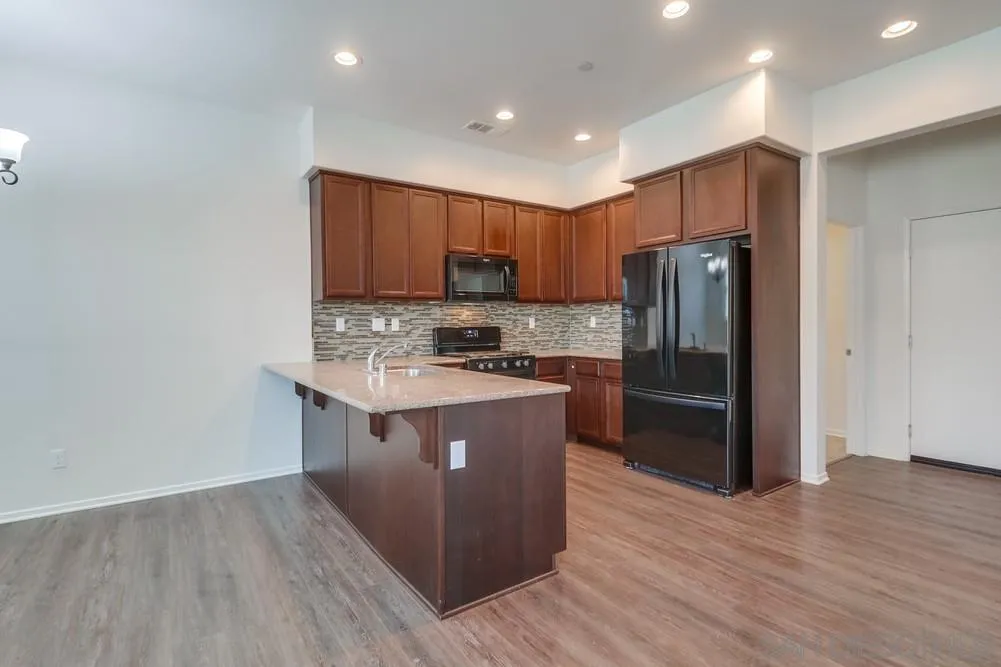 1257 Idanan Road, Unit 3 Chula Vista, CA 91913 - Photo 12 of 40 a kitchen with stainless steel appliances granite countertop a refrigerator stove a sink and a oven with wooden floor