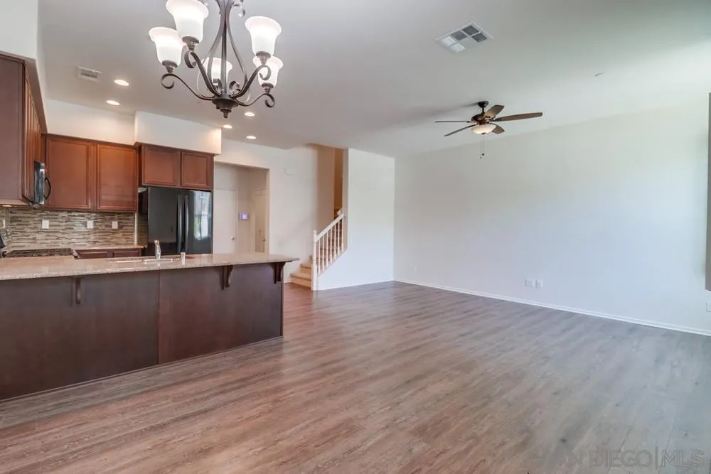 1257 Idanan Road, Unit 3 Chula Vista, CA 91913 - Photo 6 of 40 a kitchen with stainless steel appliances granite countertop a refrigerator a sink dishwasher a stove and a dining table with wooden floor