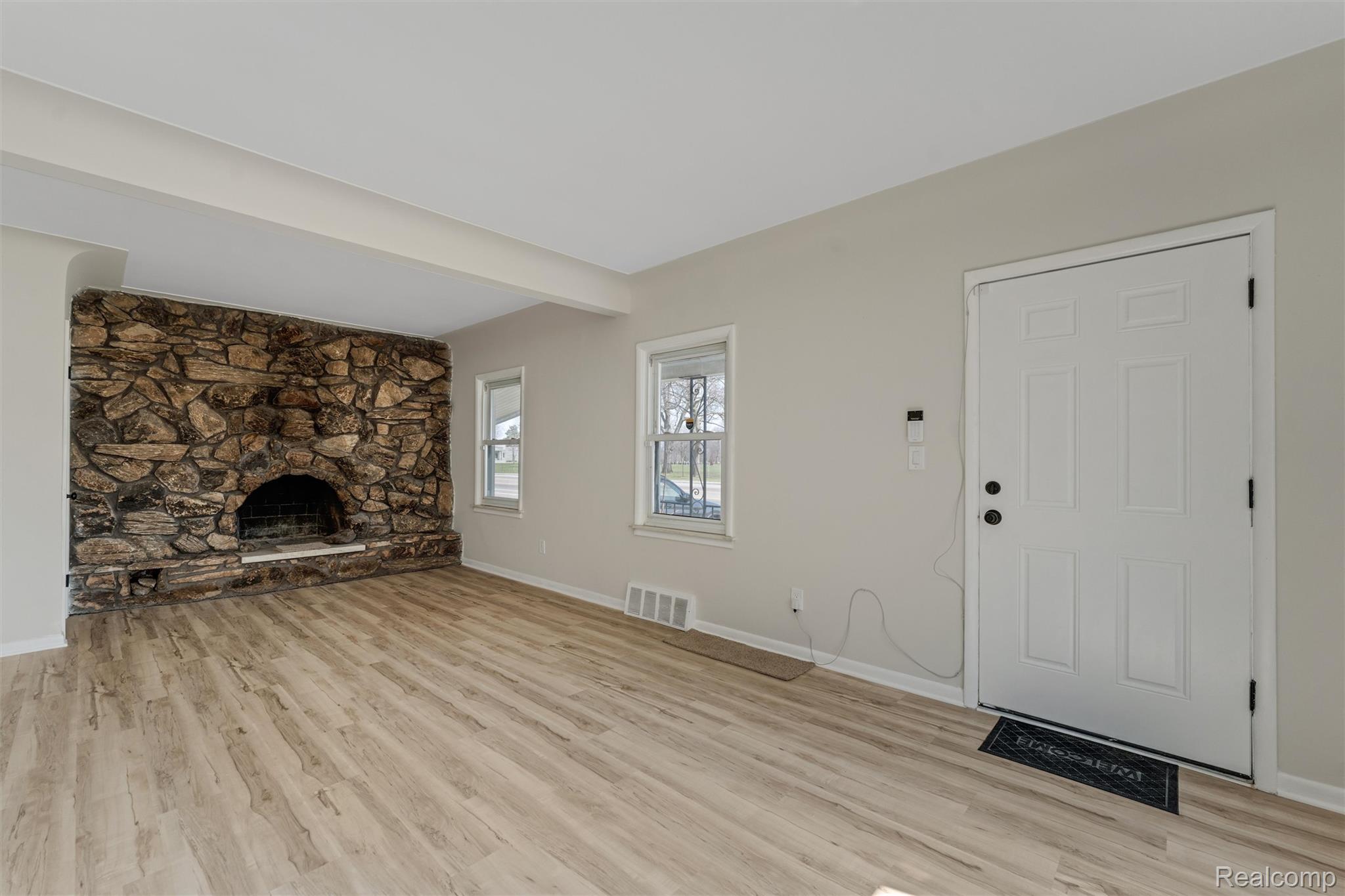 917 Perry Street Pontiac, MI 48340 - Photo 10 of 37 Unfurnished living room featuring a stone fireplace, light wood finished floors, and beam ceiling