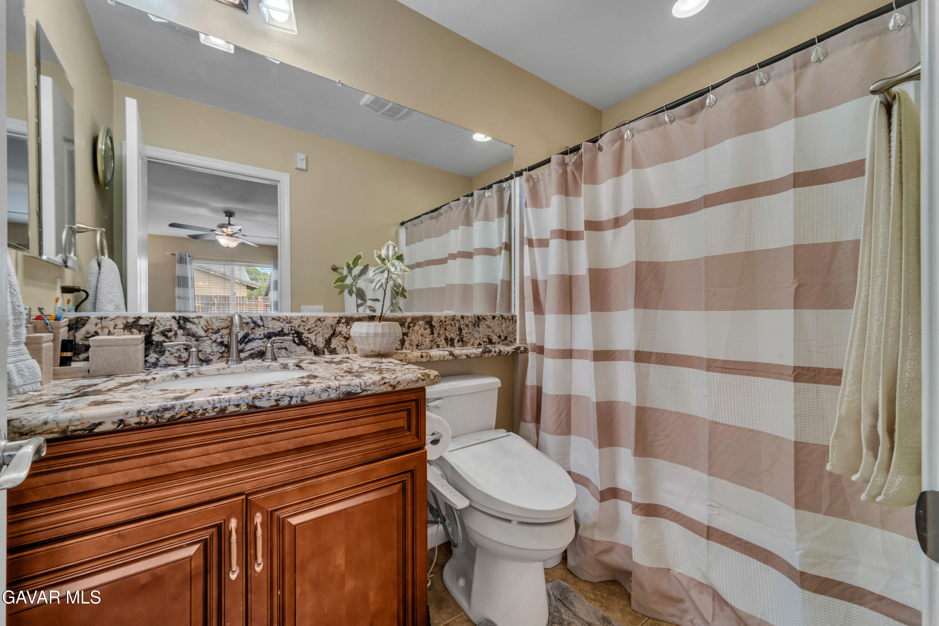 1415 Richfield Avenue Rosamond, CA 93560 - Photo 10 of 21 a bathroom with a granite countertop sink a toilet a mirror and shower