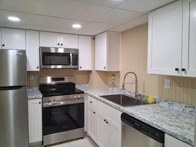 a kitchen with appliances a sink cabinets and a window