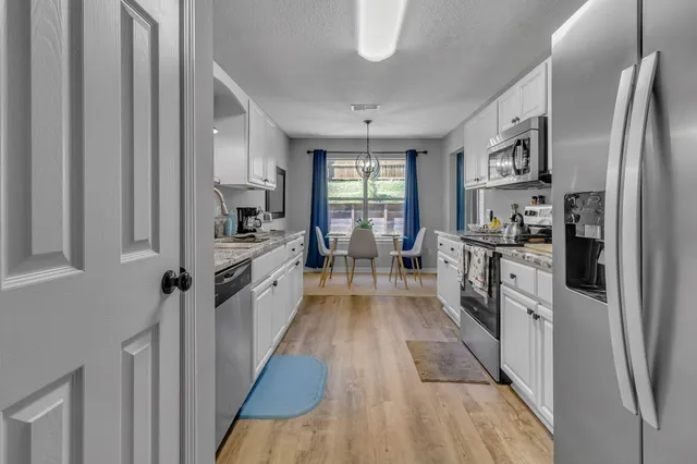 a large kitchen with a large window a refrigerator and stainless steel appliances