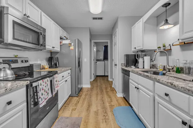 a kitchen with stainless steel appliances granite countertop a refrigerator a stove top oven a sink dishwasher and wooden cabinets with wooden floor