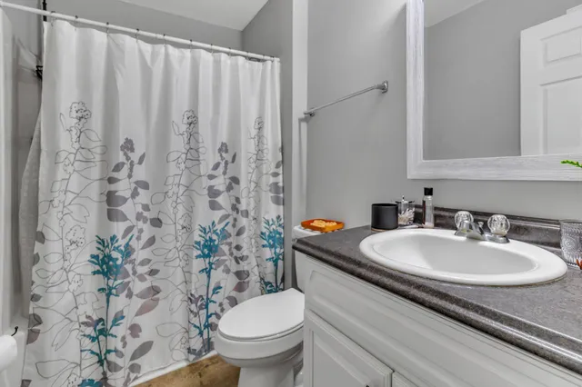 a bathroom with a granite countertop sink and a toilet