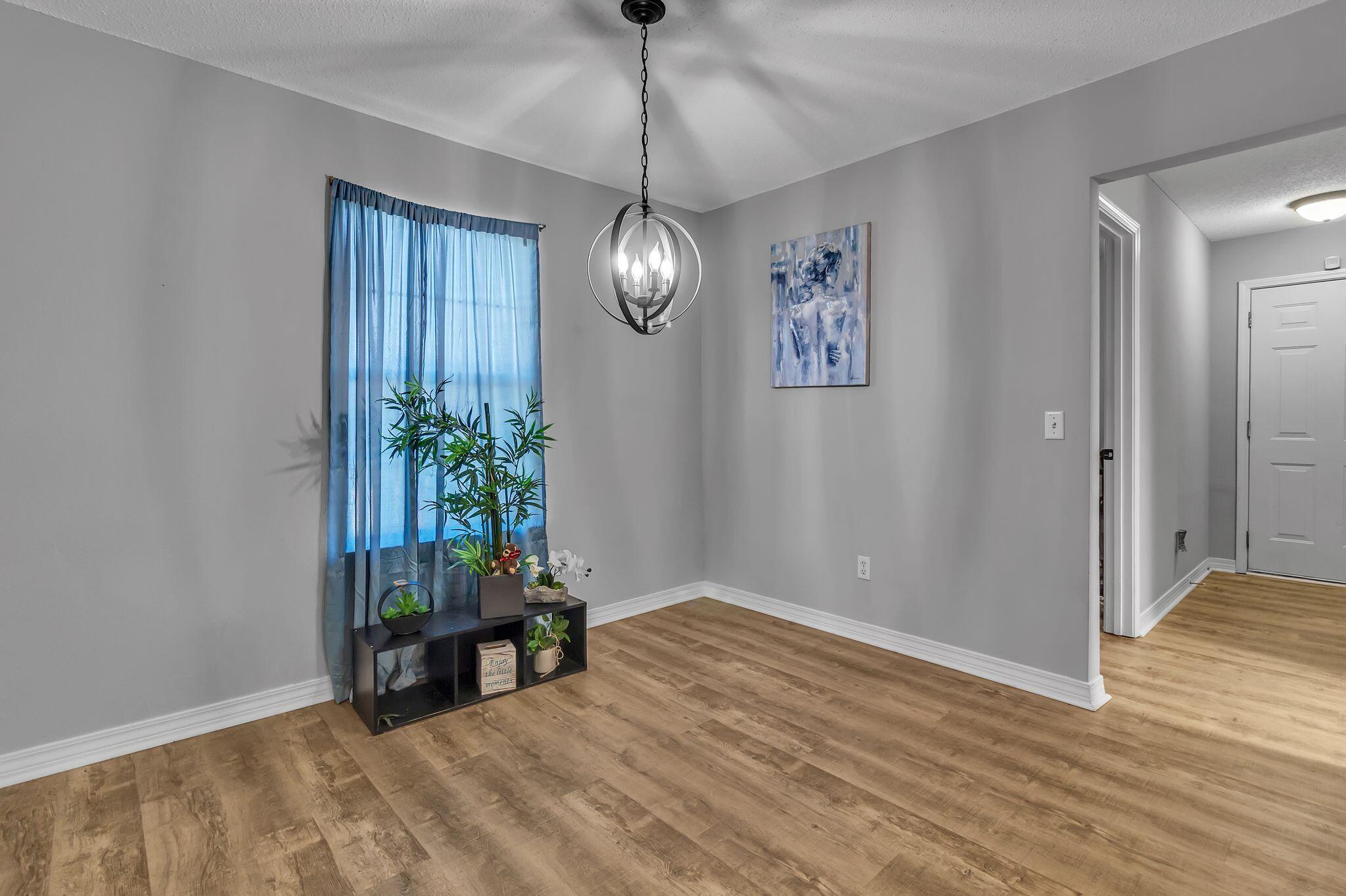 205 Trish Drive Crestview, FL 32536 - Photo 9 of 32 a view of an empty room with wooden floor and a chandelier