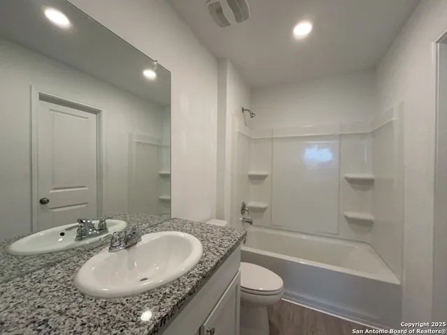 a bathroom with a granite countertop sink a toilet and bathtub