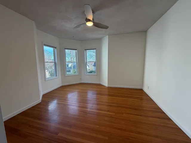 a view of an empty room with window and wooden floor