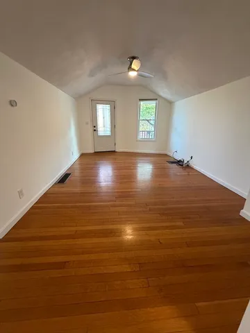 a view of an empty room with window and wooden floor