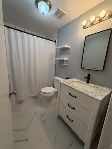 a bathroom with a granite countertop sink a toilet and mirror