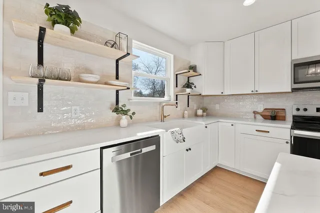 a kitchen with stainless steel appliances white cabinets a sink and a stove