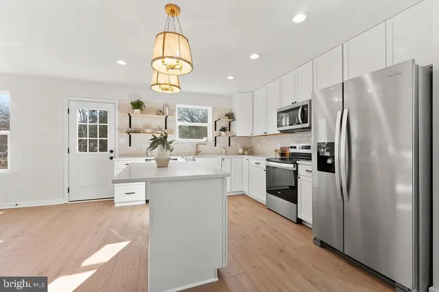 a kitchen with kitchen island granite countertop appliances cabinets and a sink