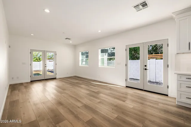 an empty room with wooden floor and windows