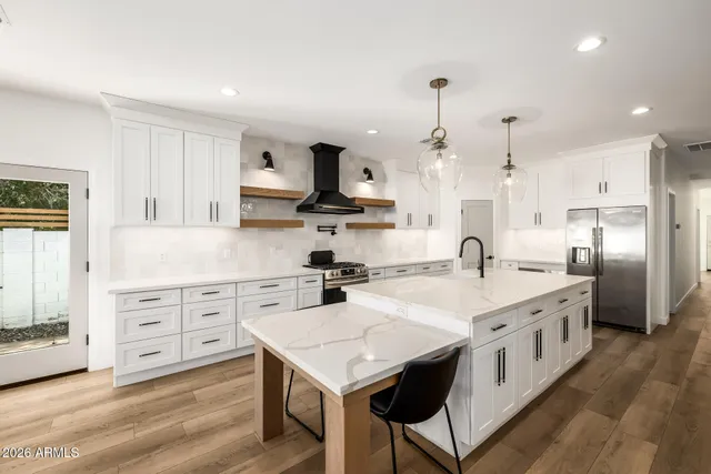 a kitchen that has a lot of white cabinets and stainless steel appliances