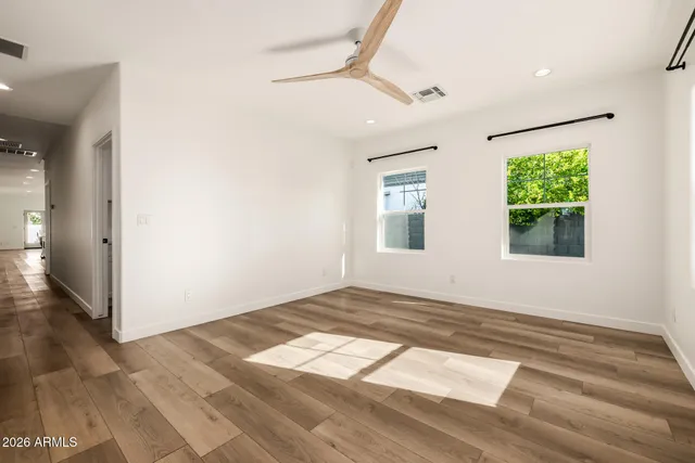 a view of empty room with wooden floor and fan