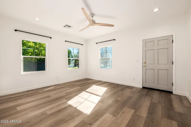 a view of an empty room with wooden floor and a window